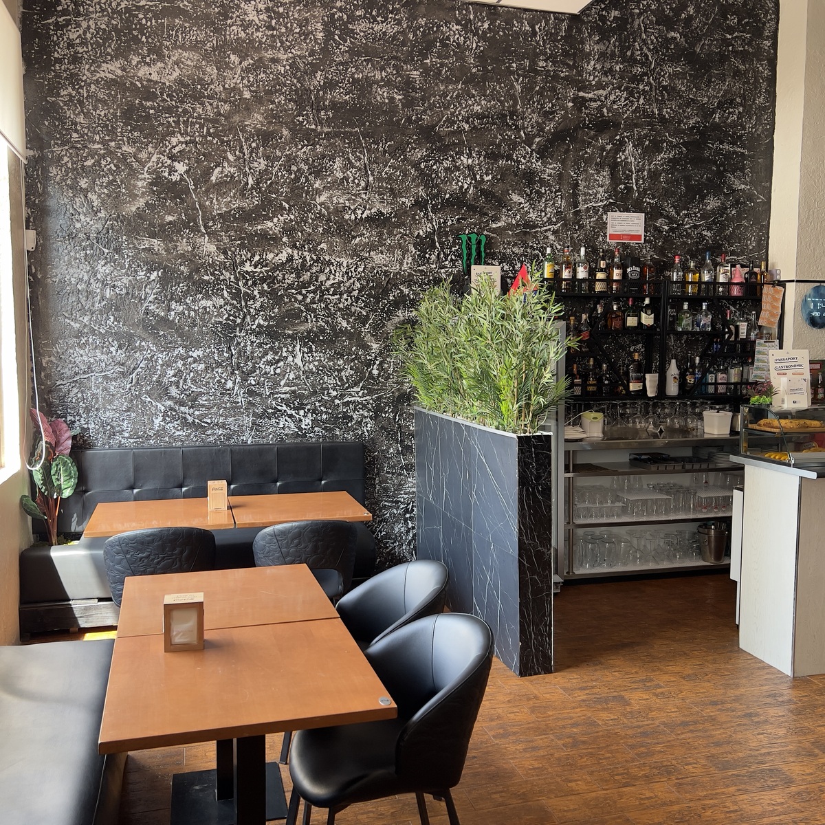 Mesas del comedor junto a la pared de mármol negro
